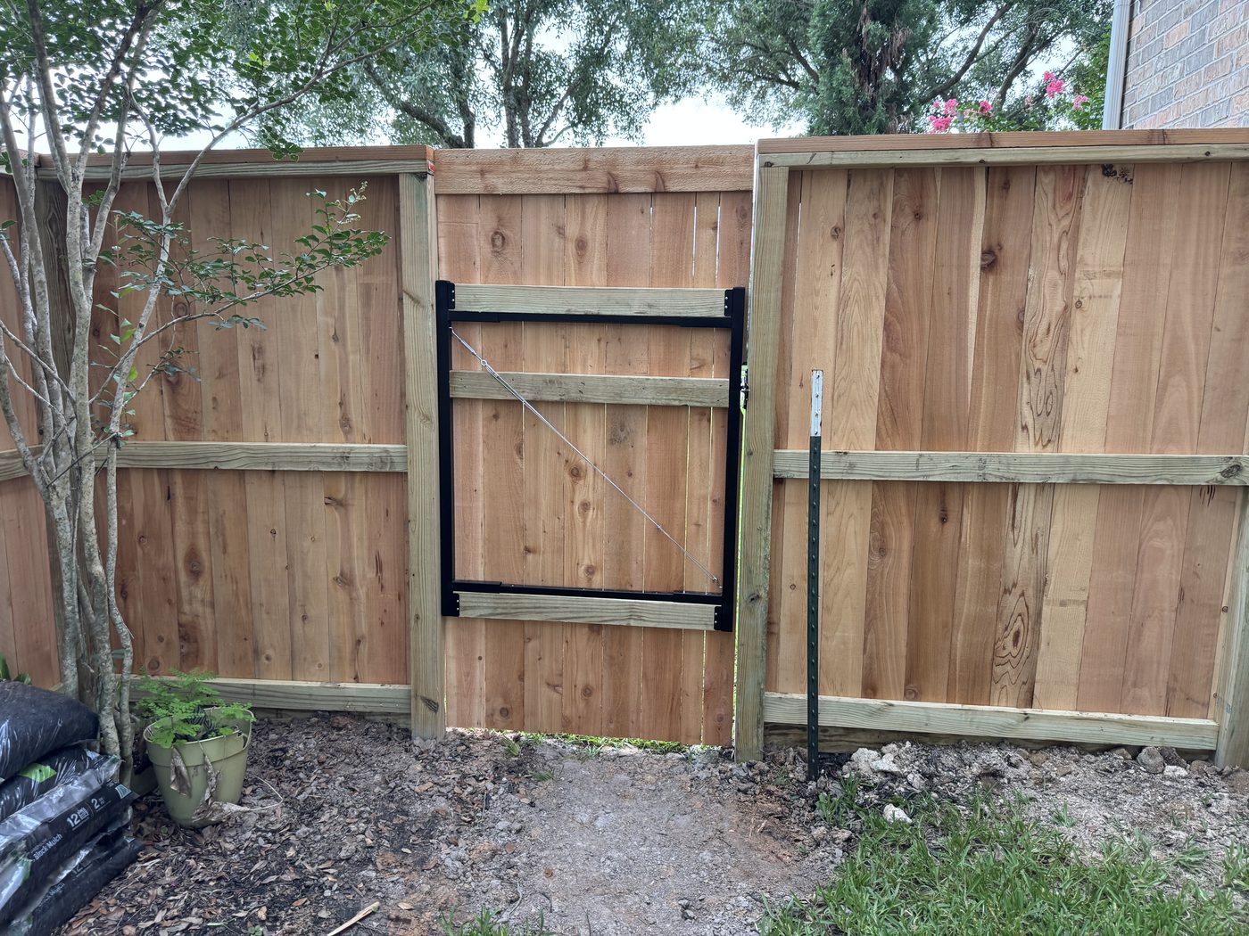 Cedar privacy fence with a tubular-steel anti-sag gate and rot board